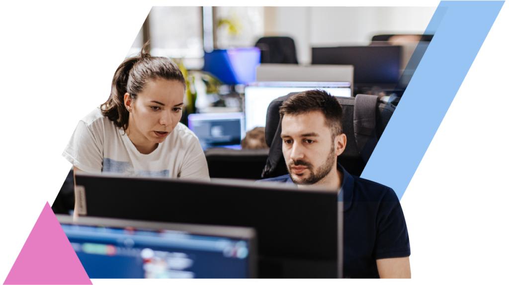 Two colleagues collaborate intently at a computer screen in a modern office setting.
