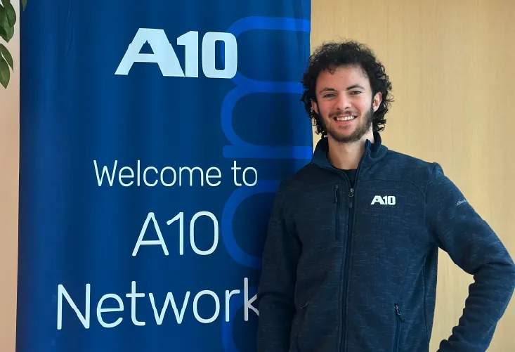 Man smiling beside an A10 banner that reads Welcome to A10 Networks.