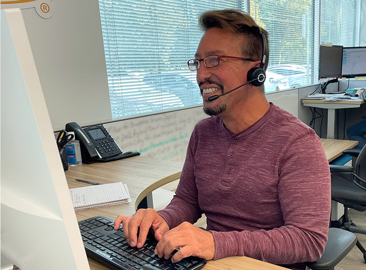 Derek Schneider sitting at his desk using the computer