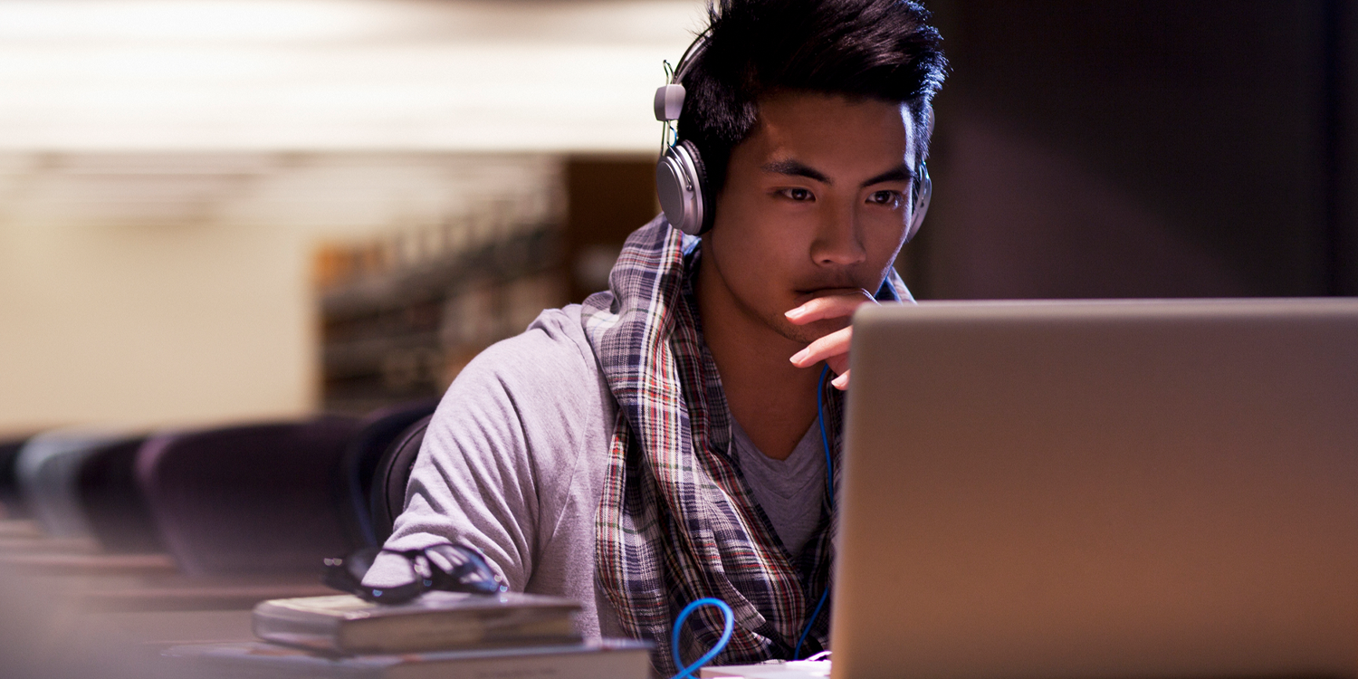 Technology professional wearing headphones and seated infront of a laptop computer