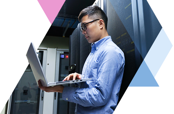 Business professional standing in a server room holding a laptop