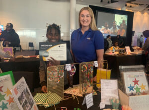 Katie Heyd alonside an event attendee standing in front of an event booth at the fair